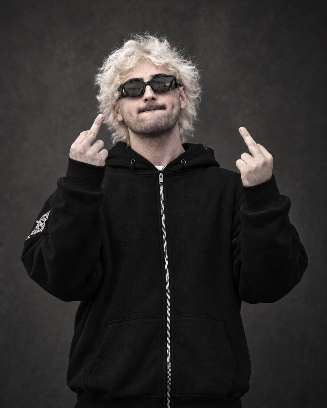 Noè Pizzetti, capelli biondi e occhiali scuri, ritratto su fondo grigio